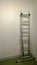 Modern iron ladder leaning against a white wall in the assembled condition during repair in apartment or office