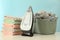 Modern iron, laundry and pile of towels on white table