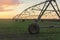 Modern irrigation system on a farm field at sunset.