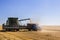 Modern John Deere combine harvesting grain on a storage trailer