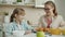 Modern kid using smartphone smiling when mother bringing fresh pastry for breakfast