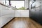 A modern kitchen with white and black fronts and a large corner window, vinyl panels on the floor.