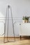 Modern lamp next to white cupboard with flowers in grey living room interior. Real photo