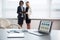 Modern laptop on foreground at empty workplace. Young businesspeople on background