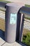 Modern LED light on side of thick stone column surrounded with metal fence next to paved sidewalk