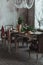 Modern loft dining room with high ceiling, vintage armchairs, empty grey concrete wall, wooden floor, dining table with