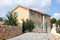 Modern Mediterranean villa with new facade and open blue wooden window blinds with traditional stone driveway in front closed with