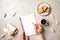 Modern minimal home workspace desk with human hand writing text message on blank paper notebook, waffles, dry flowers on concrete