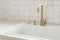 Modern minimal kitchen design. Stylish brass faucet and white granite sink on counter at window in new scandinavian house. Modern