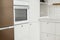 Modern minimal kitchen design. Stylish white kitchen cabinets with brass knobs, wooden shelves and appliances in new scandinavian