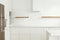 Modern minimal kitchen design. Stylish white kitchen cabinets with brass knobs, wooden shelves and appliances in new scandinavian