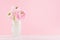 Modern minimalist bouquet of ranunculus in exquisite white frosted glass vase on white wood table and pastel pink color background