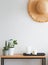 Modern minimalist light interior in details. Straw hat on the wall over the small wooden console