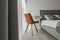 Modern minimalistic bedroom interior design in grey shades with light green bed, eucalyptus in glass vase.