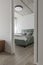 Modern minimalistic bedroom interior design in grey shades with light green bed, eucalyptus in glass vase, concrete ceiling.