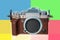 Modern mirrorless digital camera in retro style close-up, black, metal, body without a lens on a colored geometric background, the