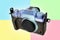Modern mirrorless digital camera in retro style close-up, black, metal, body without a lens on a colored geometric background, the