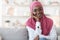 Modern Modesty. Smiling black woman in hijab posing on sofa at home