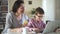 Modern mother and son spending time together, sitting at table with laptop in home interior spbd.
