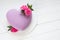 Modern  mousse cake .Heart shape  cake covered with purple chocolate velour and decoraited of pink roses.White wooden board.