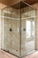 Modern new glass walk in shower with beige tiles.