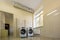 Modern new industrial washing machines on rubber insulation mats in clean light tiled bathroom or laundry room with air