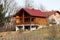 Modern newly built wooden log house with big open porch in front and new roof tiles on side of small hill