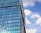 Modern office building exterior. Blue glass facade and blue sky with sparse clouds.