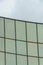 Modern office building facade with sleek glass pannels and gray skies in the late afternoon shade in urban area of city