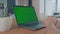 Modern opens green screen laptop to demonstrate video call on table in office