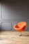 Modern orange armchair in minimal grey living room interior with