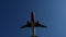 Modern passenger plane flies overhead, in the center of the frame. Beautiful blue sky in the background