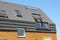 Modern passive house roof with attic skylight windows, solar water heater, solar panels, asphalt shingles