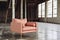 modern peach armchair with brass legs in a highceiling loft, concrete floors