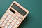 modern peach colour pastel calculator and white button on green background, business and finance concept