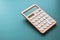 modern peach colour pastel calculator and white button on green background, finance accounting concept
