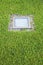 Modern quadrangular metal spotlight led lamp for outdoor use with square shape recessed in a grass floor