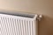 Modern radiator on beige wall. Central heating system