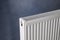 Modern radiator on grey wall, closeup. Central heating system