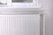 Modern radiator on wall under window indoors. Central heating system