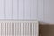 Modern radiator on white wooden wall. Central heating system