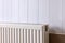 Modern radiator on white wooden wall. Central heating system