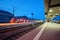 Modern railway station with passenger train on railroad track at night in Nuremberg, Germany. Fast red commuter train