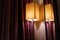 Modern rectangle lampshade and reflection in mirror on wall with red ornate curtains.