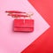 Modern red leather female bag with a gold shoulder chain isolated on a pink-red graphic background with copy space.