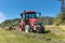 Modern red tractor in the agricultural field. Work on an organic farm. Haymaking. Tractor on a green field
