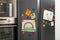 Modern refrigerator with child`s drawings, notes and magnets