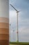 Modern renewable energy wind turbines at a wind park during cloudy day, tower of large wind turbine in front