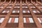 Modern residential building features a facade made of orange firebricks. Windows pattern on a industrial, brick covered exterior