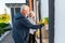 Modern retired couple smiling broadly while cleaning windows outside together